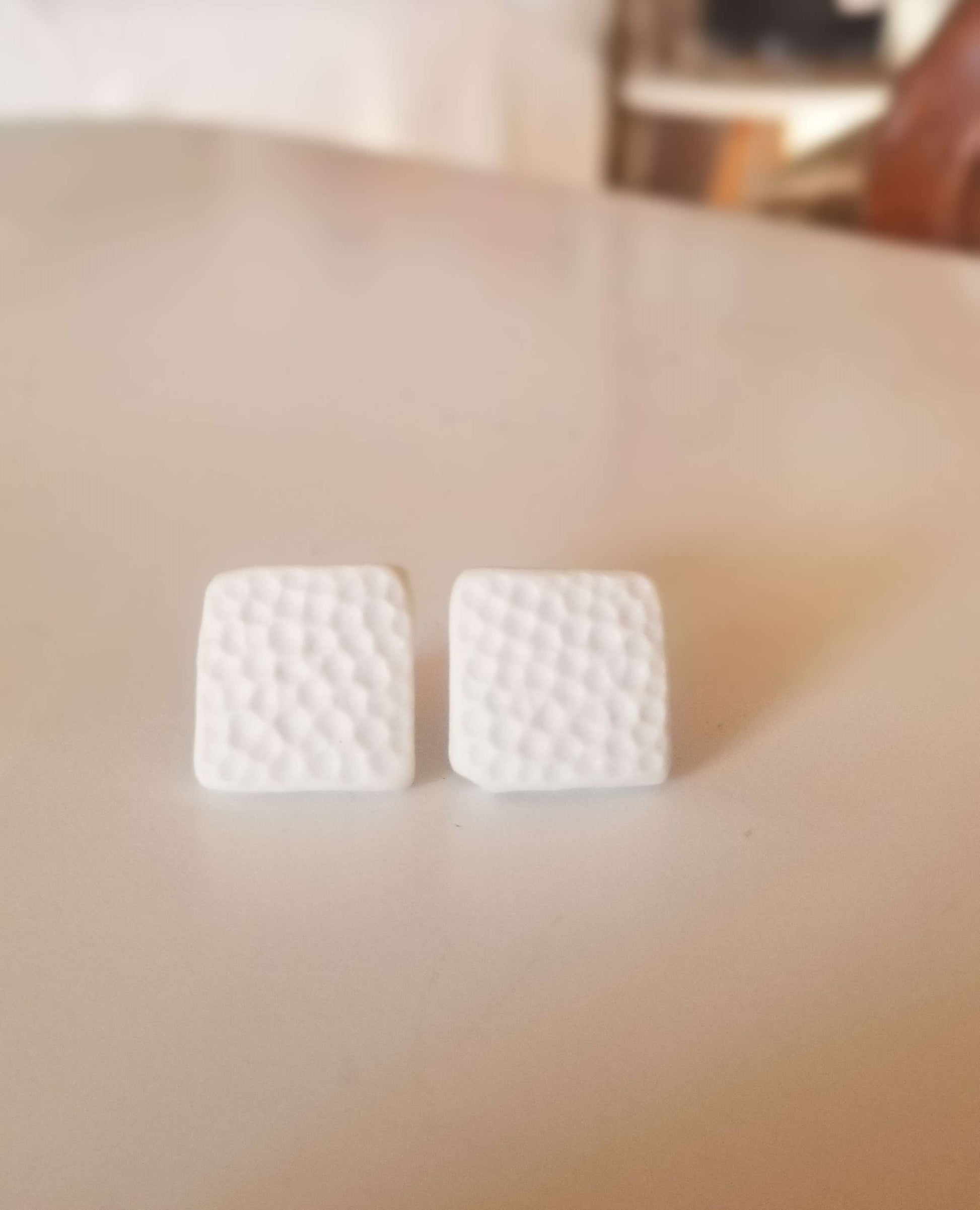 Dimpled square white studs, close up. Handmade pottery. Handmade ceramics.