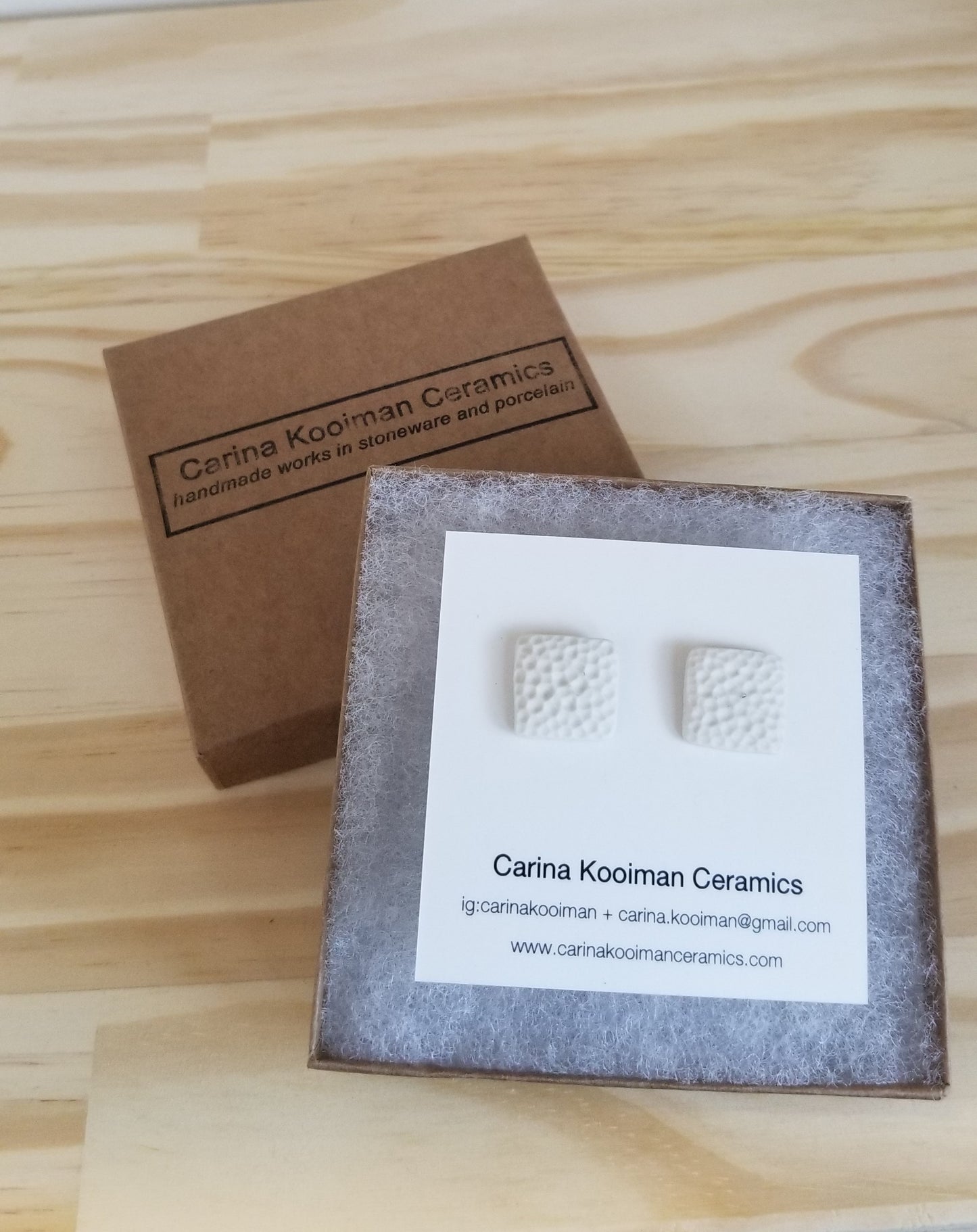 Dimpled square white studs, in packaging. Handmade pottery. Handmade ceramics.
